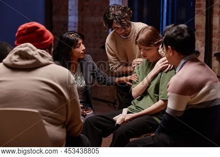 Horizontal Shot Of Psychologist And Clients Comforting Young Woman Crying During Group Therapy After