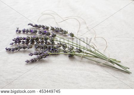 Fresh Lavender Sprigs Tied Up With Twine Laying On Natural Linen Fabric. Close Up With Selective Foc