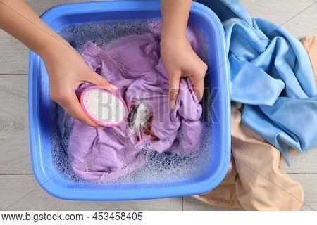 Woman Adding Powdered Detergent Into Basin With Clothes, Top View. Hand Washing Laundry