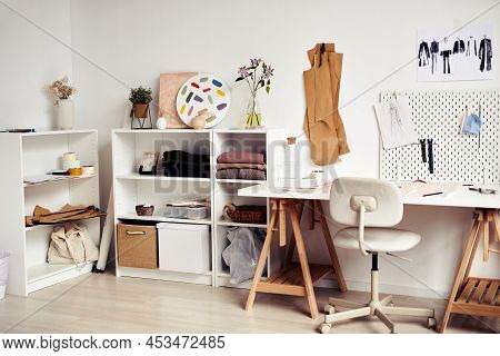 Desk And Shelves With Sewing Patterns, Various Fabric And Fashion Sketches In Tailoring Atelier