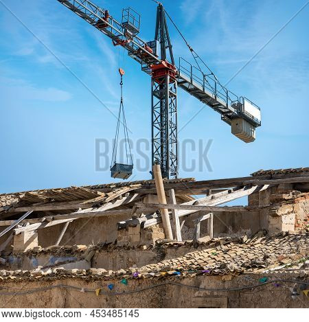 Gray And Red Crane And A Damaged Roof With Terracotta Tiles (pantiles, Coppo In Italian Language). O