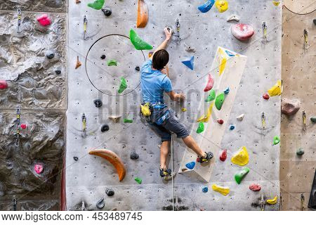 The Climber Trains On The Artificial Rock Wall With Insurance In Bouldering Gym, April 2022, Prague,