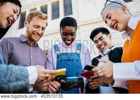 Group Of Happy Young Friends Using Mobile Phone Outdoors - Millennial Generation Diverse People Shar