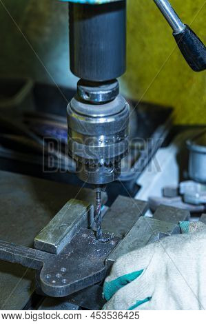 Metal Processing Concepts. Professional Fitter Man Using Metal Drilling Machine For Making Holes In