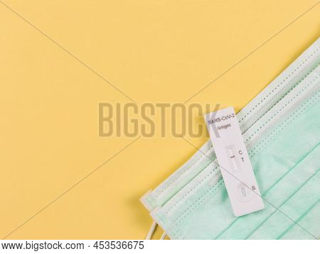 Top View Of Covid-19 Negative Test Result Antigen Test Kit (atk) On Medical Face Masks  On Yellow  B