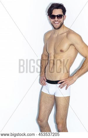 Athletic Smiling Strong Handsome Caucasian Man In Sunglasses Wearing Contrasty Underware And Posing