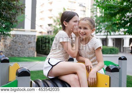 Two Pretty Teen Girls Playing On A Modern Playground In Identical Clothes. Sister, Bffs. Sisterhood,