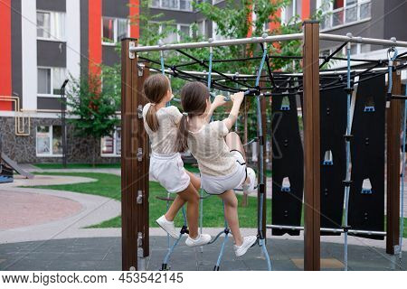 Two Pretty Teen Girls Playing On A Modern Playground In Identical Clothes. Sister, Bffs. Sisterhood,