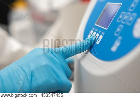 Close Up Laboratory Worker Hand In Rubber Gloves Sets Parameters On The Centrifuge For Sample Prepar