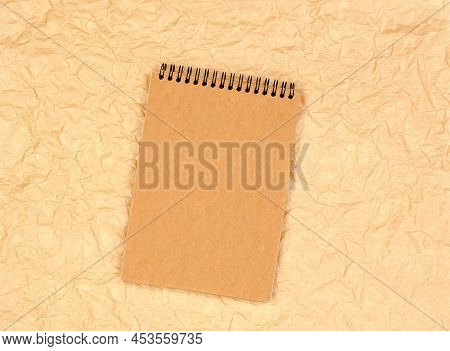 Brown Notepad With A Craftpaper On A Background Of Beige Crumpled Parchment Paper. Loose-leaf Notebo