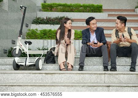 Team Of Positive Staruppers Sitting On Steps Outdoors And Discussing New Project They Are Launcing T