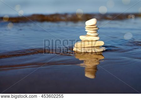 Pyramid Of Stones And Reflection On The Blue Sea Water Background, Zen Maditation, Copy Space
