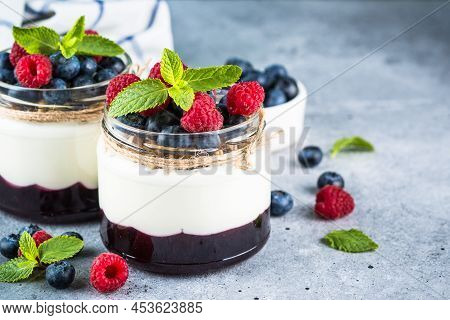 Parfait With Cream Or Yogurt, Jam And Fresh Berries In The Glass Jar. Close Up. Healthy Dessert Or S