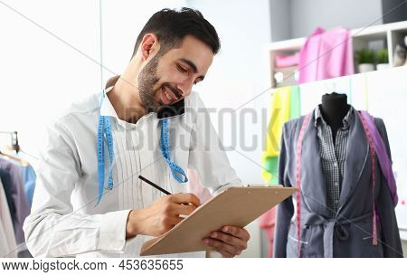 Smiling Man Tailor Speaking On Smartphone With Client. Designer Taking New Order In Atelier. Sewing 