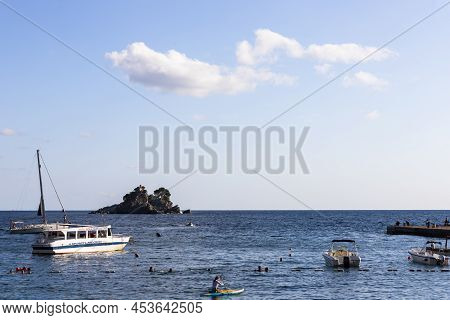 Petrovac, Montenegro, 29. August 2021: People Swimming And Enjoying Summer Vibes With Boats In Harbo