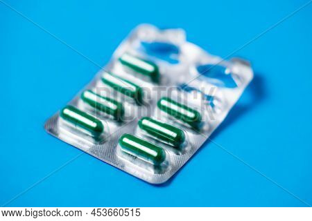 Started Packing Of Tablets With Green Capsules. Blue Background Background. Probiotics, Vitamins Con