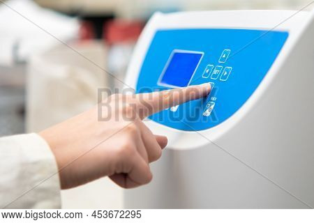 Woman Sets Parameters On The Centrifuge For Sample Preparation. Dna, Oncology Marker Analysis In Cli