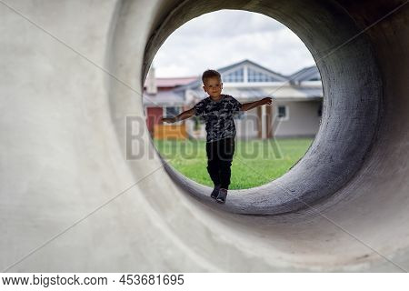 Small Boy Carefully Going Into A Grey Tunnel. Tunnel View. Brave Kid Doesn't Fear Anything