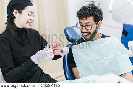 Dentist With Patient Showing A Denture, Dentist Pointing Out A Denture To A Patient, Dentist Explain