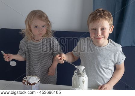 Children Smear Easter Cakes Of Homemade Cakes With Icing Before The Easter Holiday At Home In The Ki
