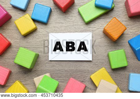 Colorful Building Blocks And Card With Abbreviation Aba On Wooden Table, Flat Lay
