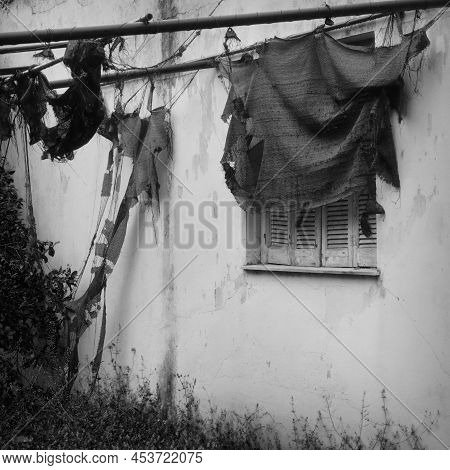 Torn Garden Tent And Window Shutter. Abandoned House Exterior Black And White.