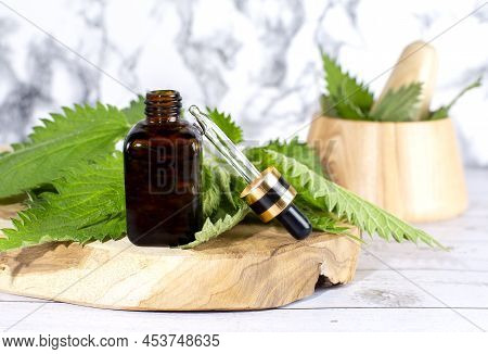Fresh Nettle In A Wooden Mortar. Preparation Of Elixirs From Medicinal Herbs By Herbalists. The Esse