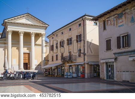 Bardolino, Italy - March 10, 2022:  The Stores And Coffee Bar In Matteotti Square With The St. Nicho