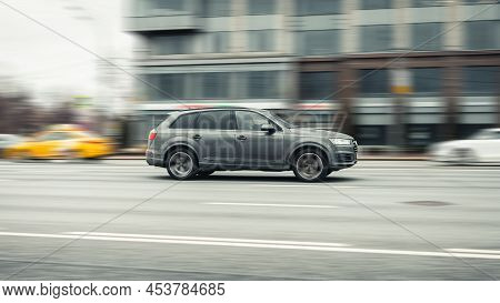 Side View Rolling Shot In Gray Color Crossover Car In Motion. Audi Q7 Driving Along The Street In Ci
