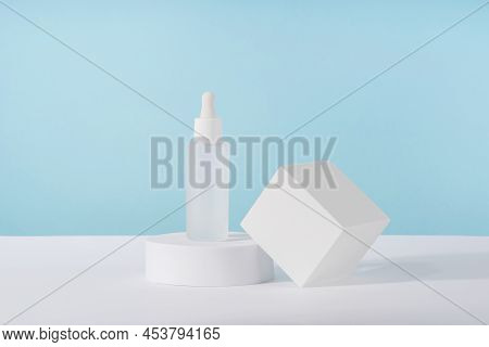 Serum Cosmetic Bottle With Peptides And Retinol On Platform Pedestal On Blue Background. Oil Cosmeti