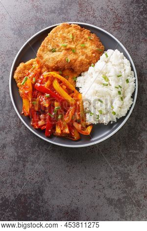 German Schnitzel Served With Paprika Sauce And Rice Close-up In A Plate On The Table. Vertical Top V