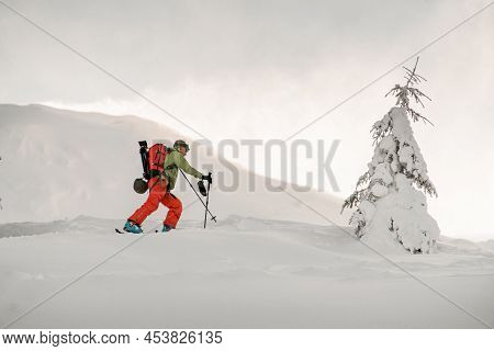 Side View Of Active Skier Climbing The Hill On Splitboard. Ski Touring In Mountains.