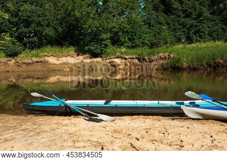Tourist Canoes With Paddles Stand On The River Coast In Summer On A Water Hike. Rafting On Inflatabl