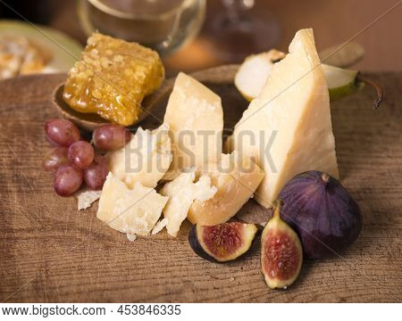 Cheese Plate Served With Grapes, Melon, Figs, Crackers, Honey, Nuts And White Wine On A Wooden Table