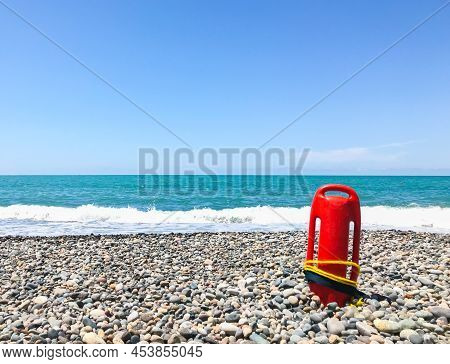 Red Rescue Float On Rocky Beach With Sea Panorama And No Lifeguard. Static Blank Space Copypaste Bac