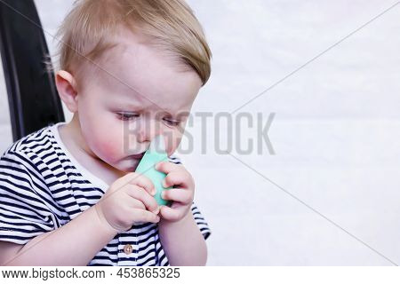 A Defocused Infant Uses A Nasal Aspirator Into The Nose, Sucking Out The Mucus. Cleansing Snot In A 