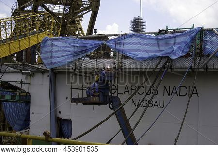 Sembawang, Singapore - Mar 2 2013: Yard Workers In A Hoisted Cherry Picker Basket, Welding Ship's He
