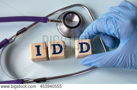A Hand In A Medical Glove Puts Cubes With The Abbreviation Idd (intellectual And Developmental Disab