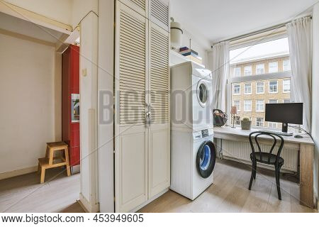 The Interior Of A Cozy Office Combined With A Laundry Room With Appropriate Equipment In A Modern Ap