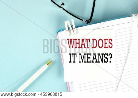 What Does It Means Text On A Sticky On A Notebook With Pen And Glasses , Blue Background