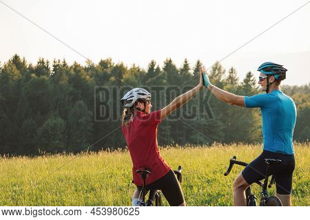 Woman And A Man On Racing Road Cycles Taking A Break After Successful Training And Looking At Sunset