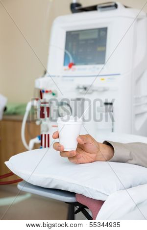 Cropped image of male cancer patient holding glass of crushed ice in dialysis room at hospital