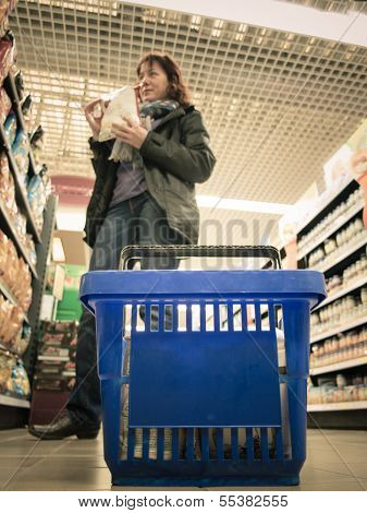 Woman Shopping With Blue Basket At Supermarket Shop. Retail.