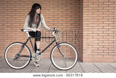 Sportive woman with fixie bike over a brick wall