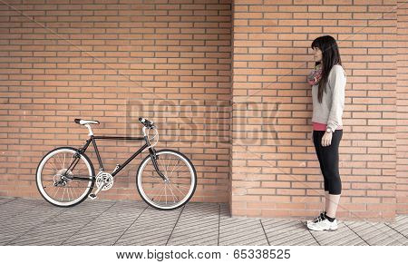 Sportive woman with fixie bike over a brick wall