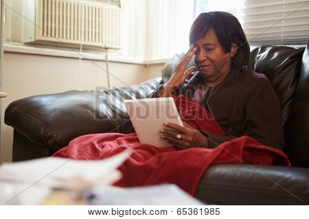Senior Woman Keeping Warm Under Blanket With Photograph