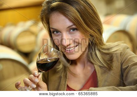 Woman tasting red wine in cellar
