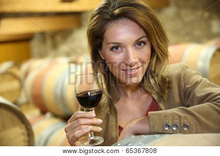 Woman tasting red wine in cellar