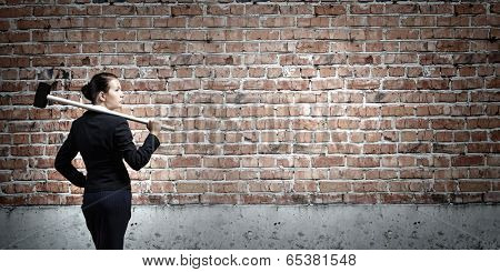 Young attractive businesswoman with hammer in hands