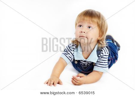 Het kleine jongetje in het donker blauwe overalls ligt op een vloer